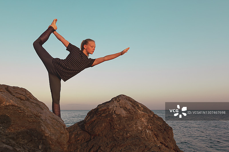 女孩在海边岩石上练习娜塔罗阇式——舞蹈之王瑜伽图片素材