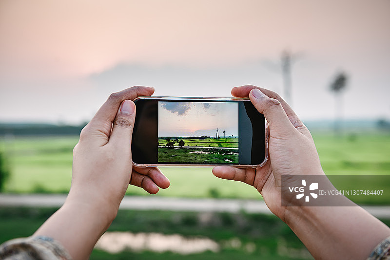 女游客日落时分拍摄乡村农田风光图片素材