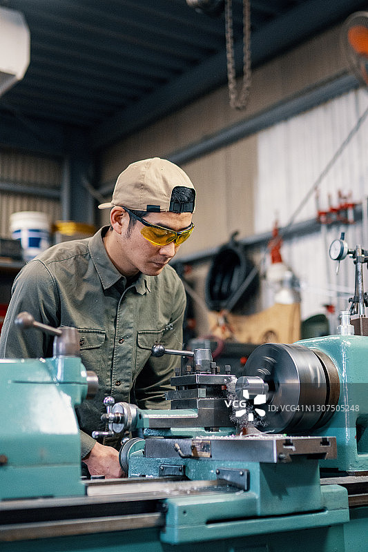 中年男子使用车床加工金属零件图片素材