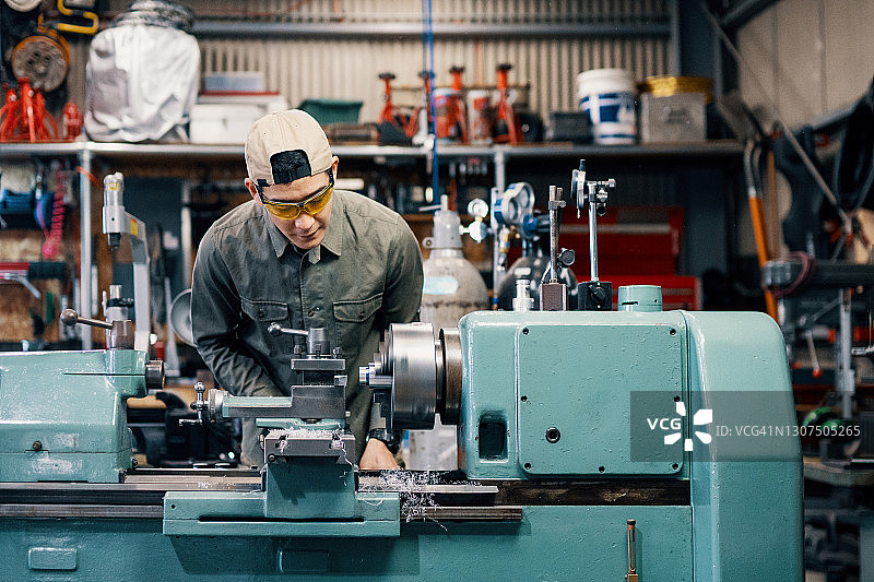 中年男子使用车床加工金属零件图片素材