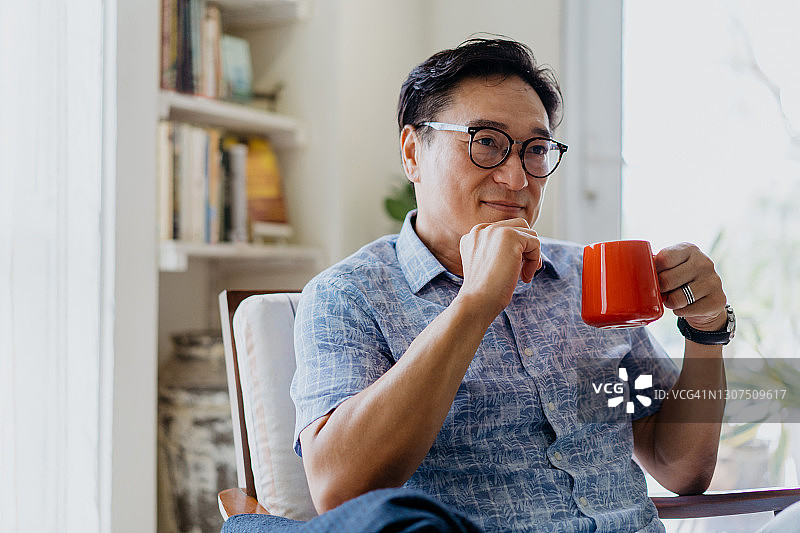 快乐的亚洲中年男人在家享用咖啡图片素材