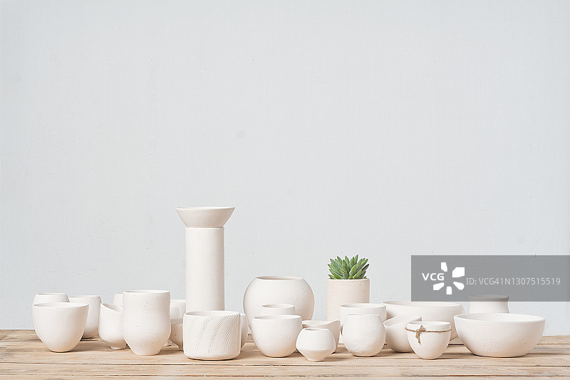 木桌上未上釉的白色陶罐图片素材