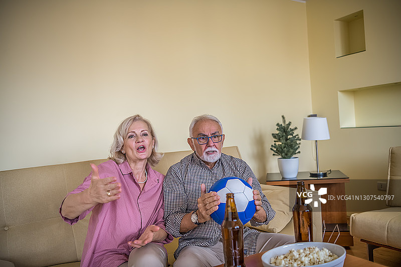 快乐的老年夫妇在家观看体育比赛图片素材