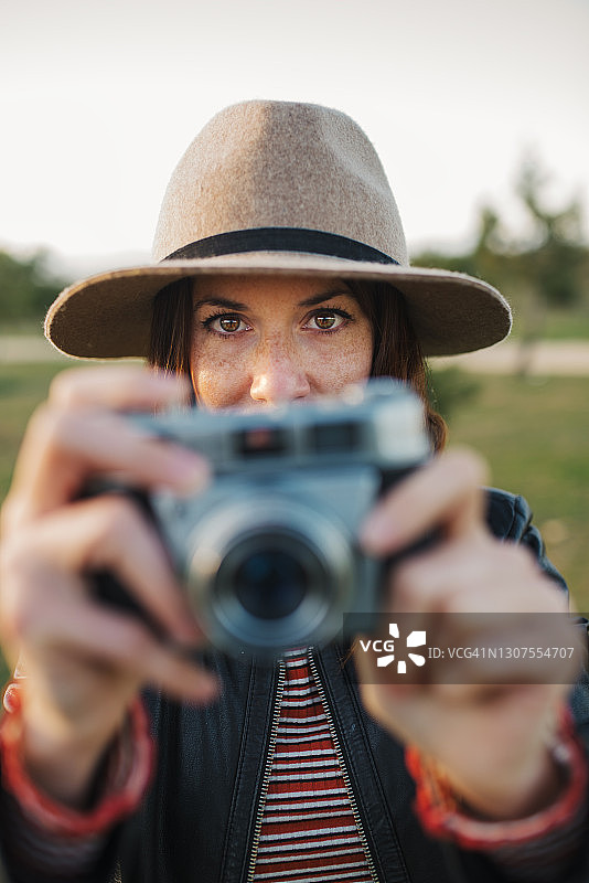 一位在乡村用模拟相机拍照的，有着绿色眼睛和雀斑的美丽女人特写图片素材