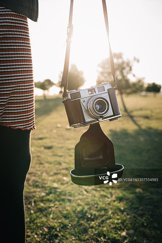 年轻白人女性手持旧式模拟相机的特写图片素材