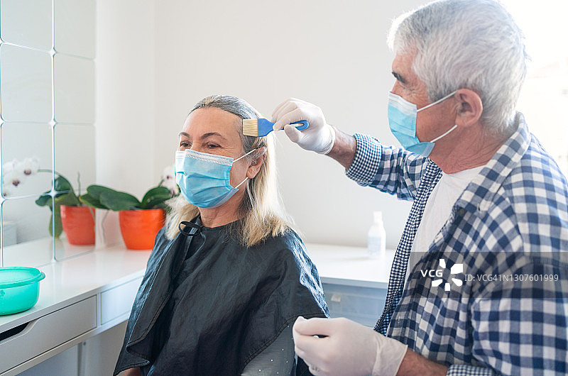 新冠疫情封锁期间，在家为妻子染发的年长男人图片素材