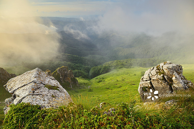 美丽山地草甸上的岩石，山毛榉林上空有云图片素材