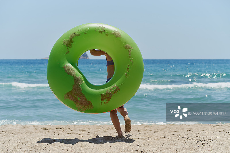 小女孩带着充气轮胎跑到海边图片素材