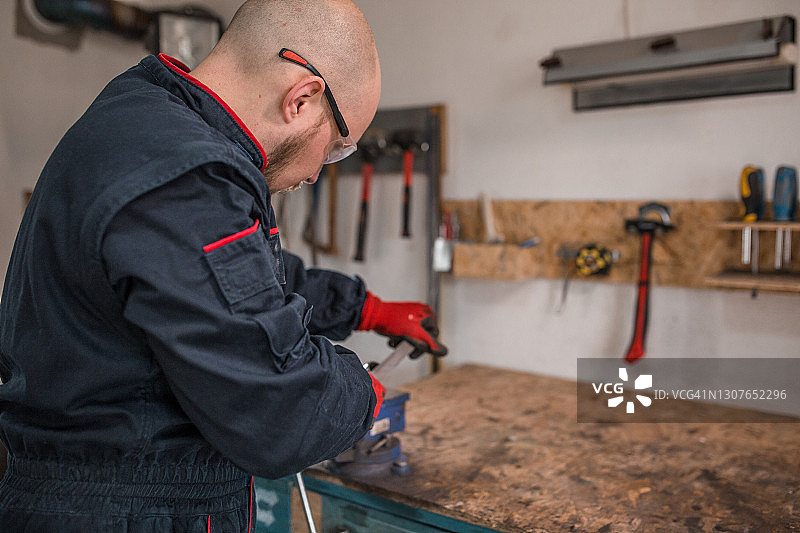 在小型金属车间使用工具的年轻男人图片素材