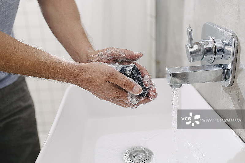 在家用肥皂和水洗手的匿名年轻人图片素材