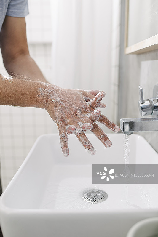 在家用肥皂和水洗手的匿名年轻人图片素材