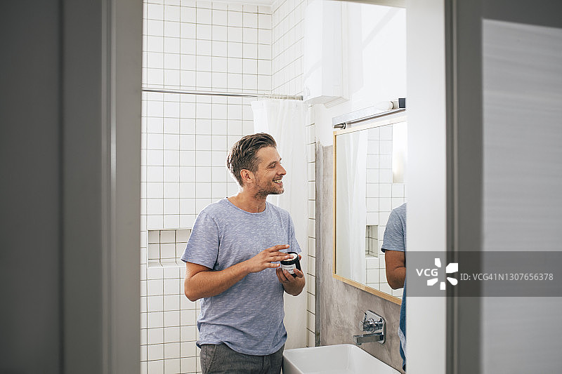 早上剃须后涂抹面霜的英俊年轻男人图片素材