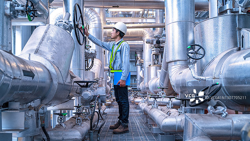 在工业区操作设备的工程师，钢制管道和阀门图片素材