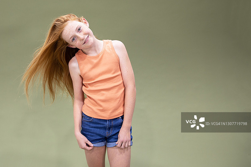 穿着橙色衬衫甩着红发的女孩肖像图片素材