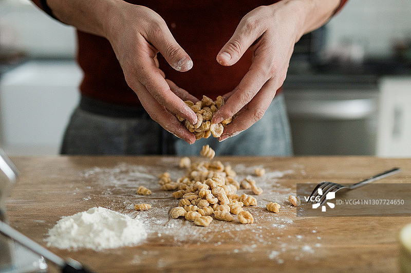 男人撒面粉在自制意大利面上图片素材