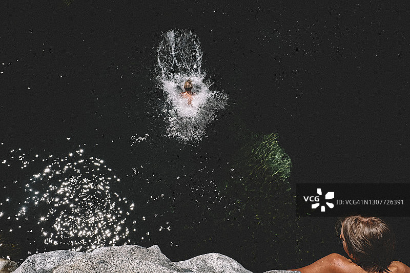 男孩在朋友的注视下完美地跳入河中图片素材