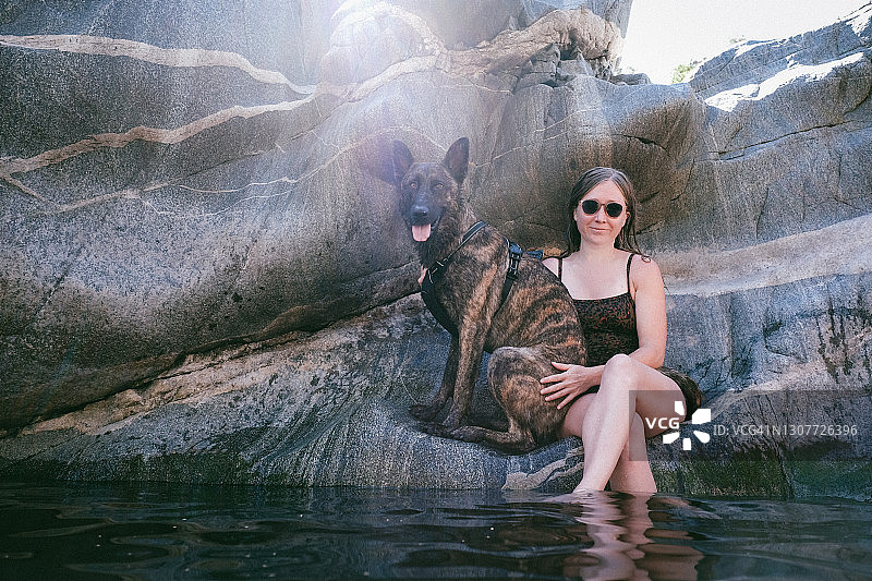 夏日，在河边对着镜头微笑的女人和狗图片素材