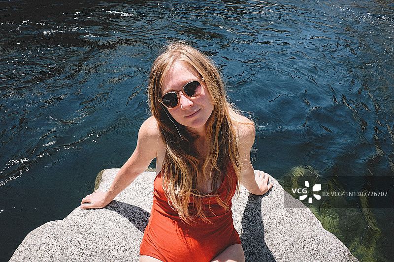 穿着红色西装和太阳镜的金发女子在夏日午后享受日光浴图片素材