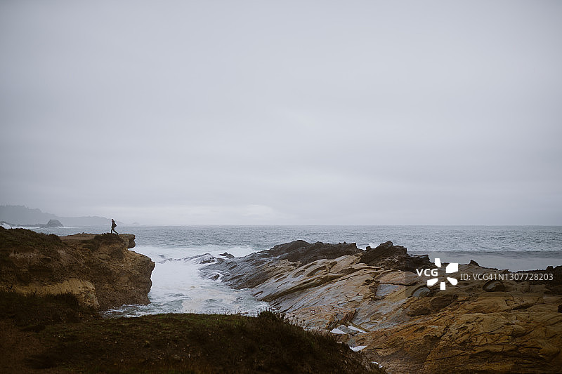 人物漫步岩石峭壁，远眺海蚀柱图片素材