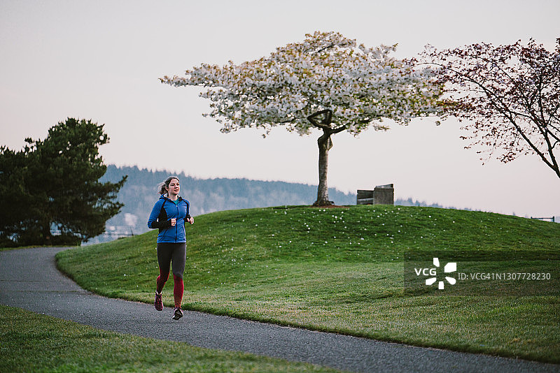 清晨在铺砌的小路上奔跑的赏樱女子图片素材