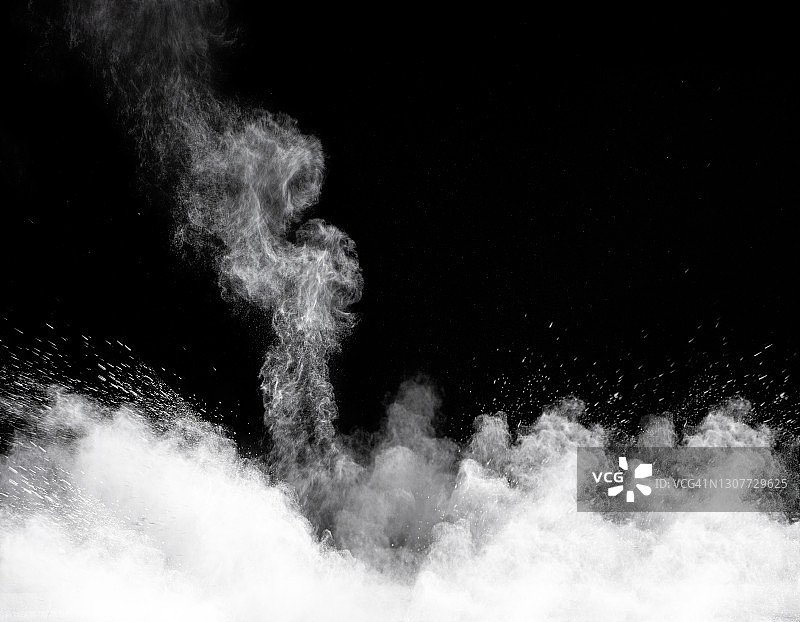 白色粉尘和烟雾颗粒在黑色背景上的冲击与爆炸图片素材