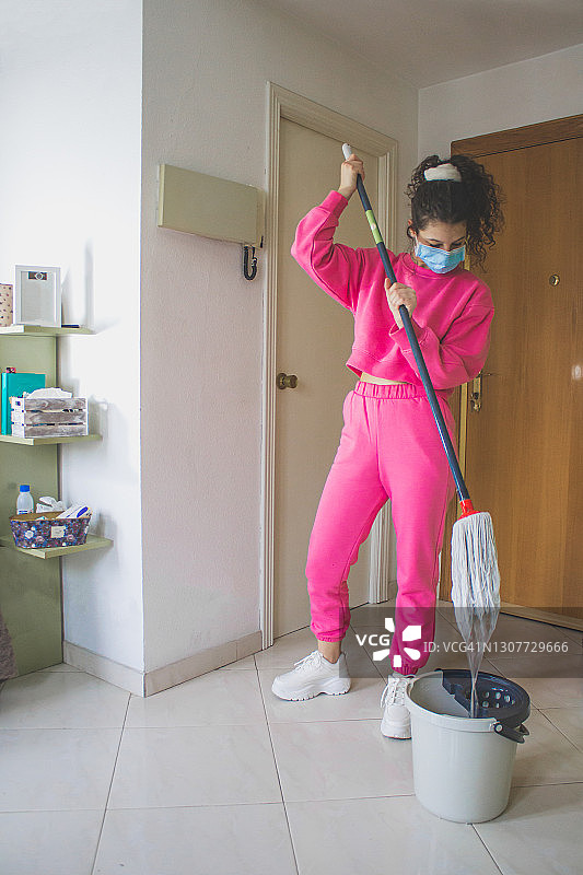身穿粉色运动服和戴口罩的女人正在拖地图片素材