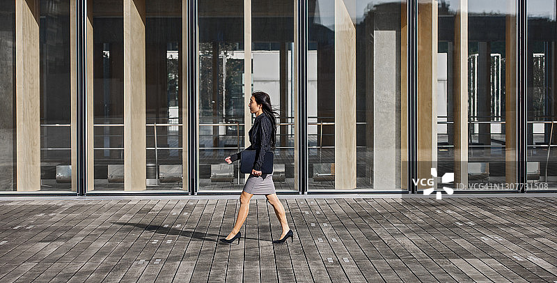 在巴黎现代建筑旁走过的商务女性图片素材