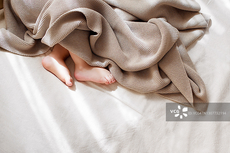 婴儿的小脚盖着轻薄的棉质针织毯图片素材