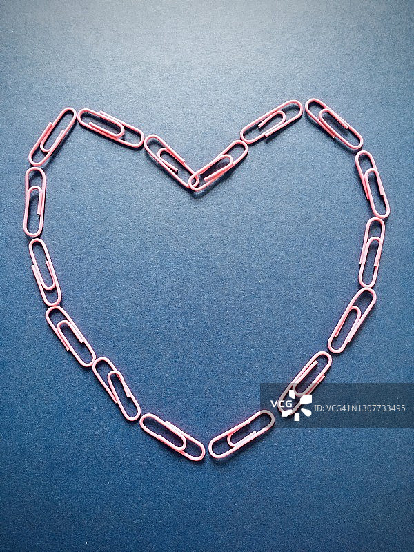 蓝色背景上的心形排列的回形针图片素材