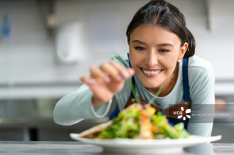 快乐的厨师在厨房里装饰盘子，同时学习烹饪课程图片素材