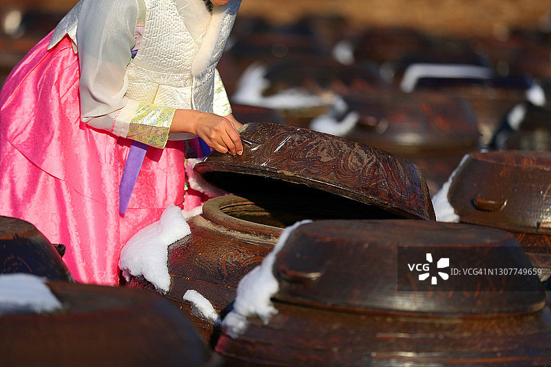 冬天，穿着韩服的女人拿着酱缸台的盖子图片素材