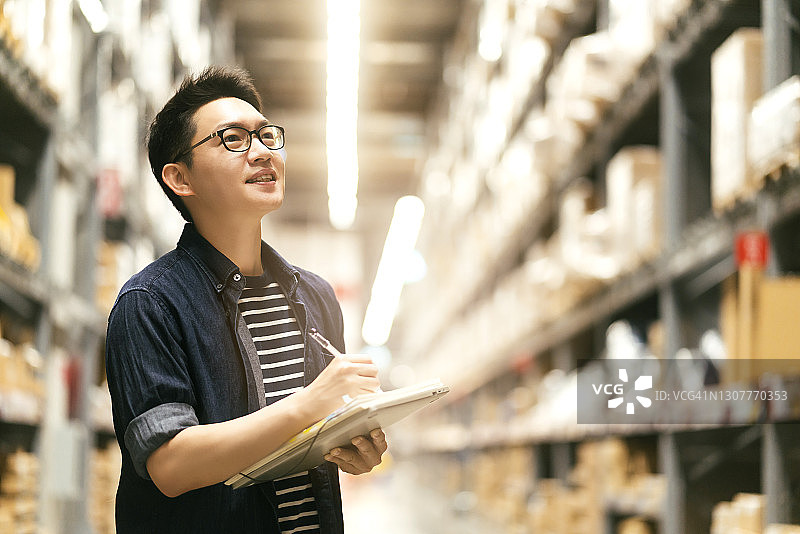 亚洲男企业主检查仓库库存的肖像图片素材