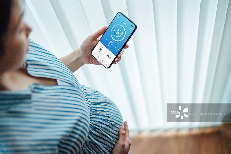 年轻女人在智能手机上使用怀孕跟踪App图片素材