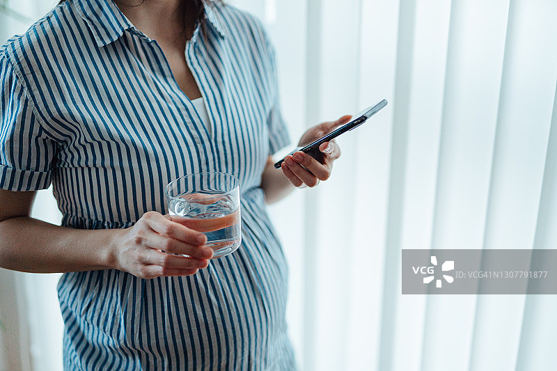 年轻女人在智能手机上使用怀孕跟踪App图片素材