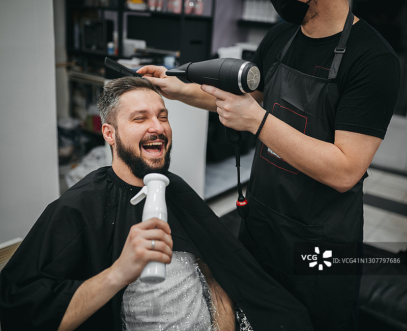 年轻帅气理发师为有魅力男人理发图片素材