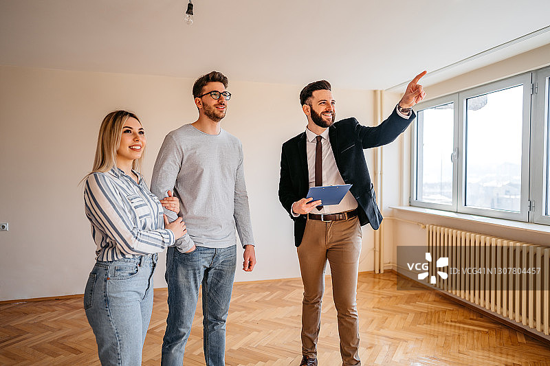 房地产经纪人向年轻夫妇展示待售公寓图片素材