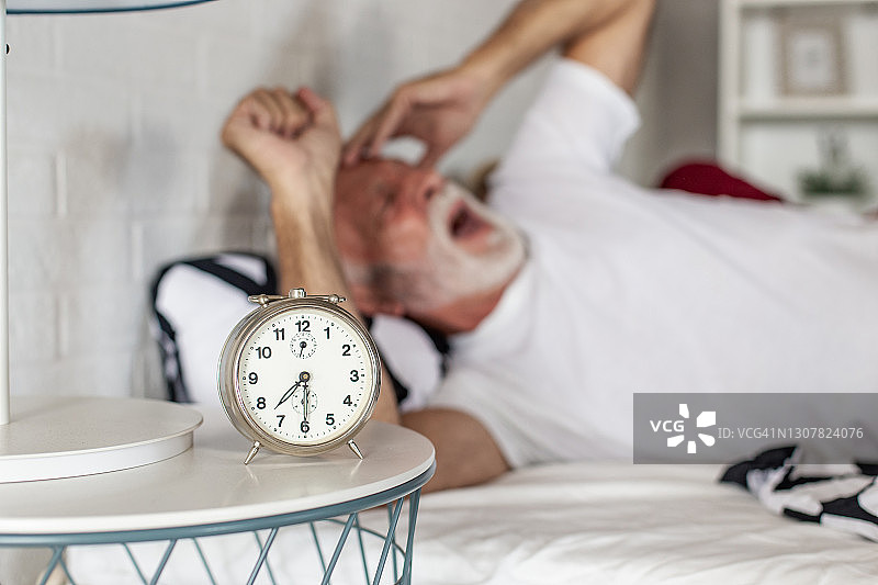 被闹钟吵醒的年长男人图片素材