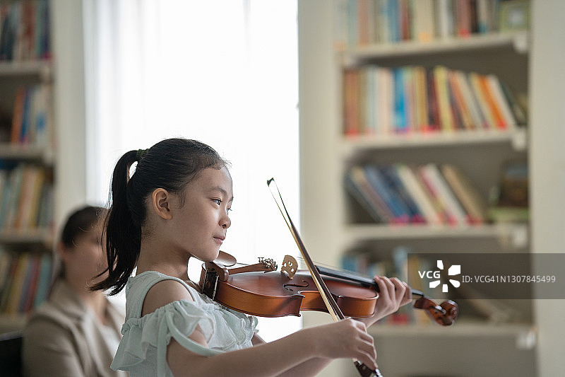 女孩在家为母亲演奏小提琴图片素材
