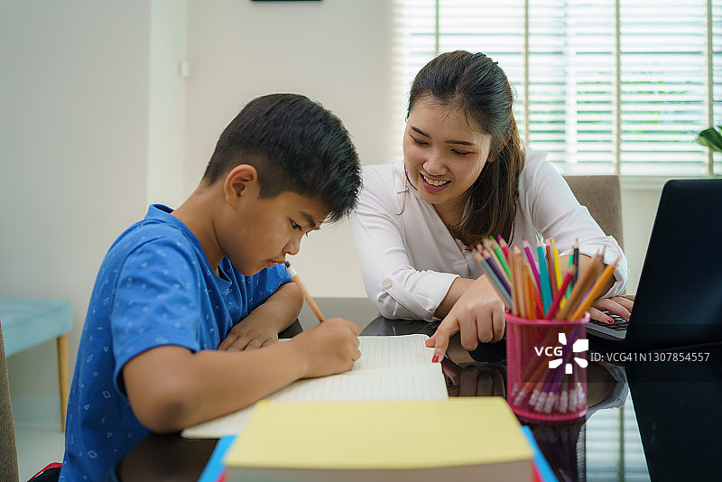 疫情期间，亚洲妈妈在家辅导儿子读书图片素材