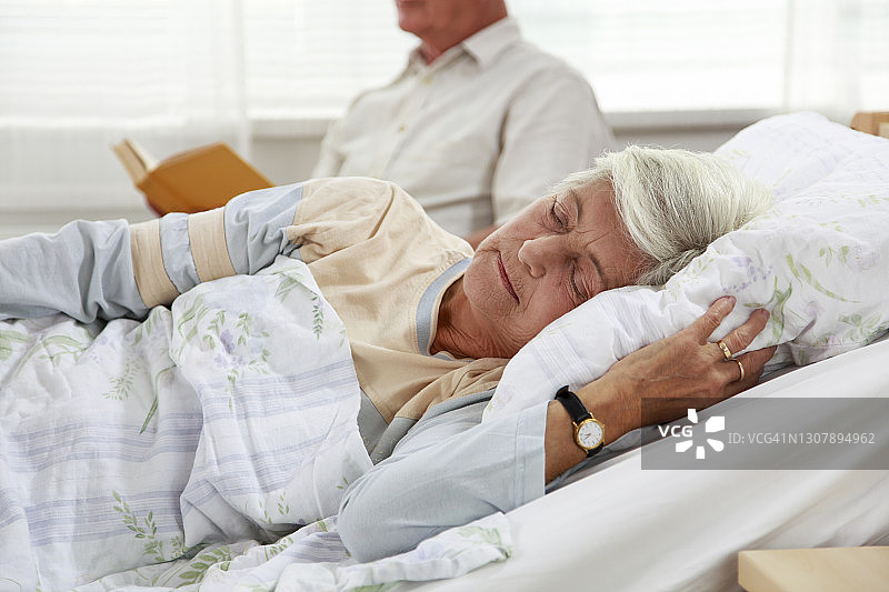 年长的男人给即将入睡的妻子读睡前故事图片素材