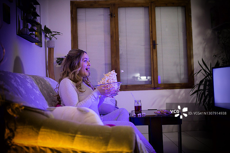 在沙发上看电影的惊讶女人图片素材