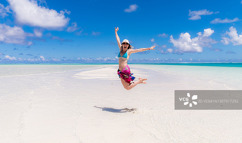 在艾图塔基泻湖的单脚岛上，裹着纱笼跳跃的女孩图片素材