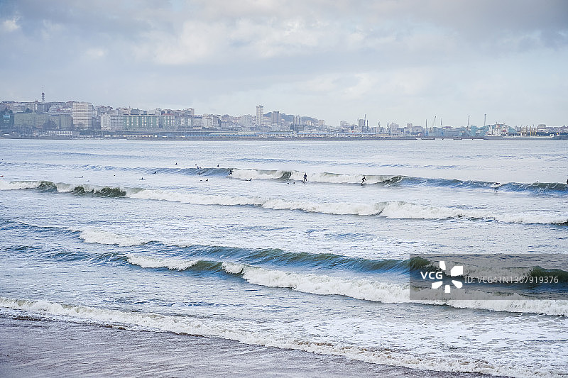 巴斯蒂亚格罗海滩的冲浪者，背景是拉科鲁尼亚市图片素材