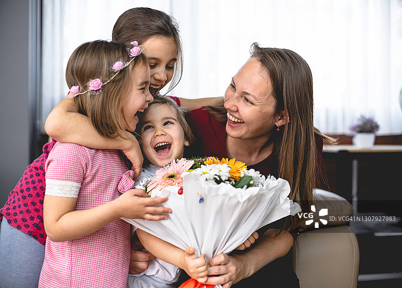 孩子们在母亲节给妈妈送上鲜花和贺卡，制造惊喜图片素材