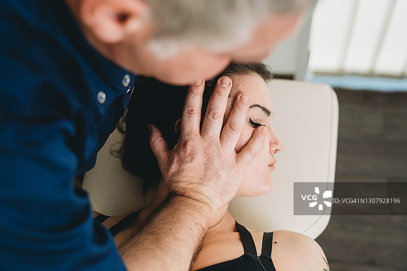 理疗师为年轻女性患者进行脊椎按摩图片素材