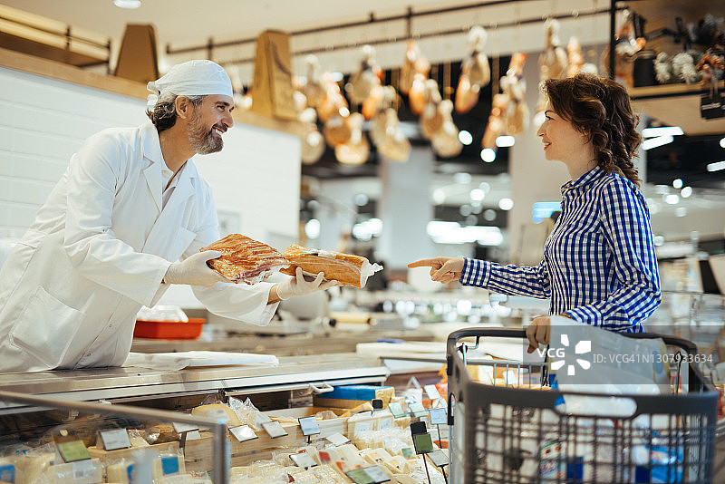 女顾客在超市的熟食柜台选择肉类图片素材