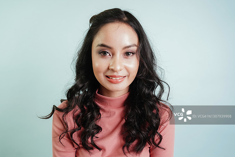 在蓝色背景下看着镜头的亚洲青少年可爱女孩肖像图片素材