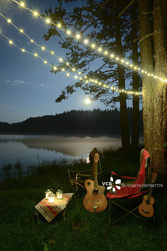 在湖岸边露营，吉他和尤克里里琴放在旅游椅旁图片素材
