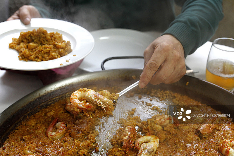 男人在盘子里盛西班牙海鲜饭图片素材