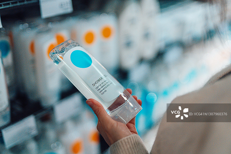 超市里拿着沐浴露瓶子的女人手部特写图片素材